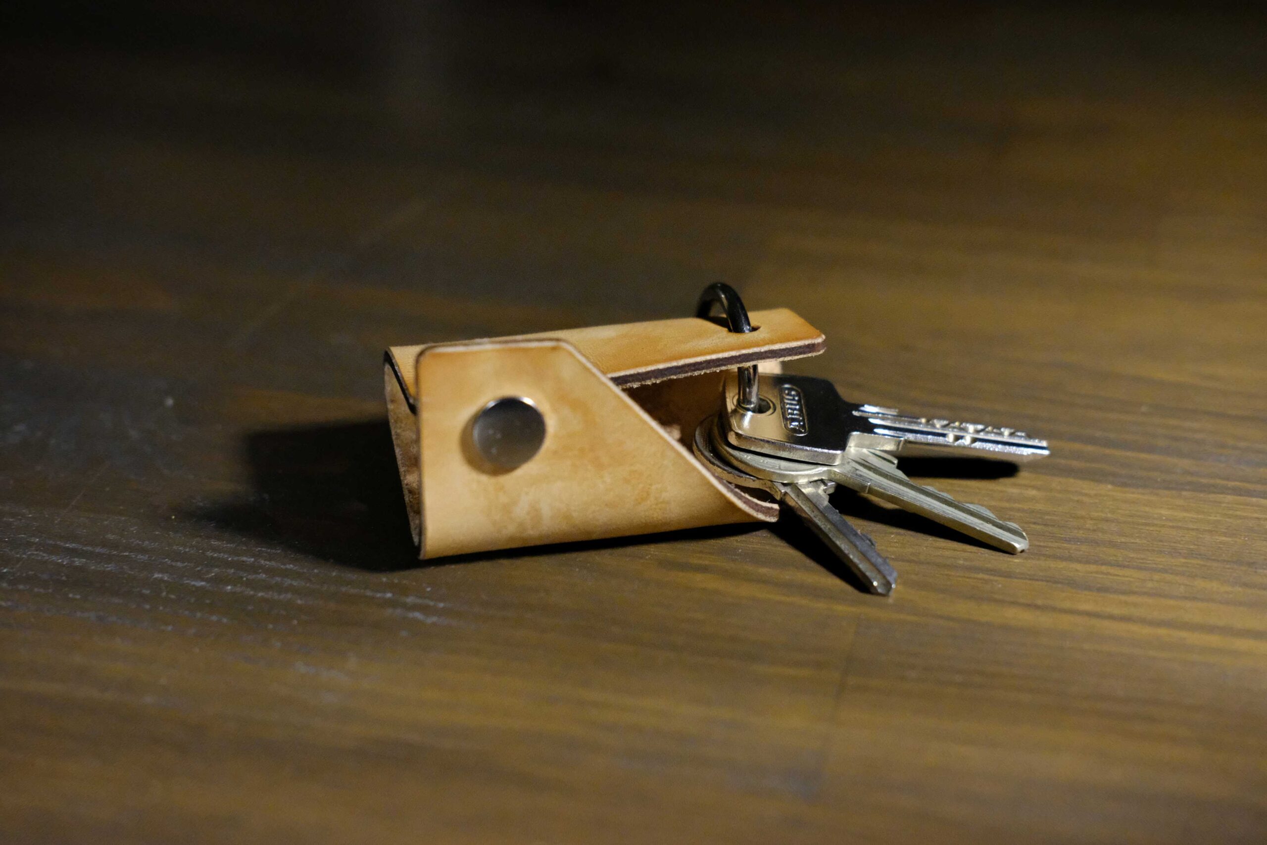 Geöffneter Schlüssel-Organizer SEPP mit Rundkarabiner und stabilen Metall-Schlüsseln auf Holzgrund.