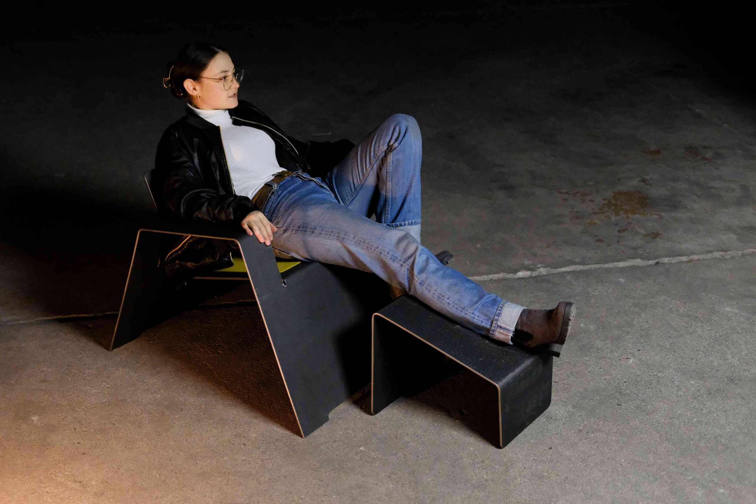 Eine Person nutzt den Ottoman Otto als komfortable Fußablage beim Sitzen im Sessel Stephan.